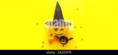 Composition with Halloween balloons, witch's hat and pumpkins on yellow background Stock Photo