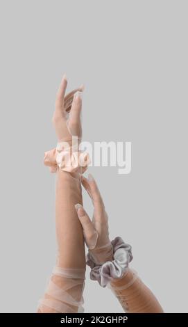 Female hands in gloves with silk scrunchies on light background Stock Photo