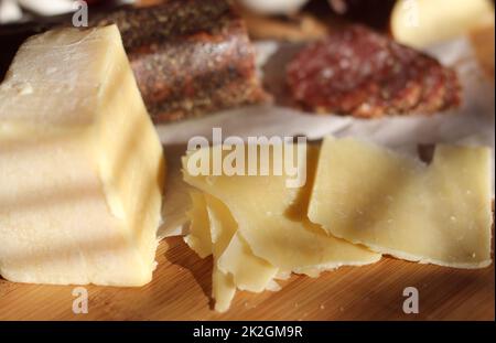 Salami au poivre sur plateau avec fromage anglais et irlandais, pommes en tranches et épices dans la cuisine rustique Banque D'Images