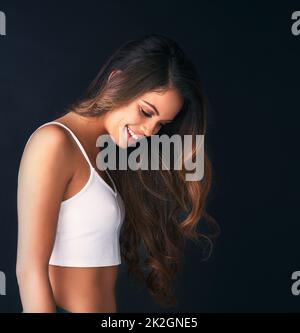 Ses poils ont eu un volume incroyable. Photo en studio d'une jeune femme attrayante posant sur un fond sombre. Banque D'Images