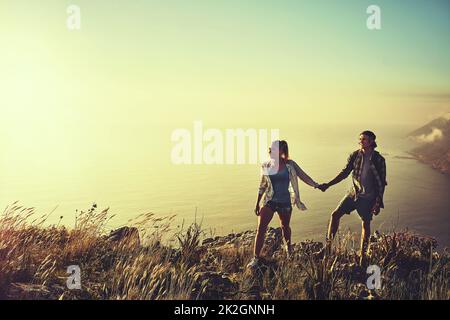 Explorons le chemin moins parcouru. Photo d'un jeune couple affectueux qui se joint lors d'une randonnée ensemble. Banque D'Images