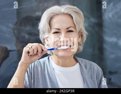 J'ai toujours toutes mes dents parce que je me fais bien attention. Photo d'une femme âgée se brossant les dents à la maison. Banque D'Images