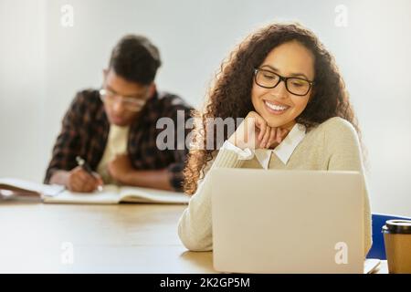 Axée sur ses études. Photo rognée d'une jeune étudiante d'université attirante travaillant sur son ordinateur portable lorsqu'elle est assise en classe. Banque D'Images