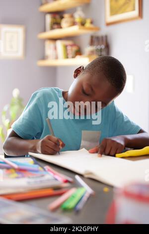 Je pourrais passer toute la journée à colorier en images. Photo d'un jeune garçon passant son temps à colorier en images. Banque D'Images