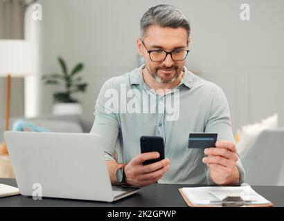 Il est temps de payer certaines factures. Photo courte d'un beau homme mature qui paie des factures tout en étant assis à son bureau à la maison. Banque D'Images