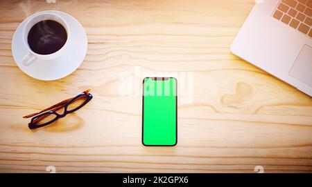 Effectue le travail seul, sans avoir besoin de mains supplémentaires. Prise de vue en grand angle d'un smartphone affichant une touche de couleur sur l'écran dans un environnement de bureau. Banque D'Images