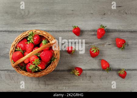 Au baby visualiser le panier de fraises, certains d'entre eux renversé sur les planches de bois gris 24. Banque D'Images