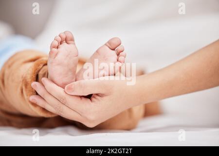 Je n'ai jamais pensé que le mercredi soit arrivé ici. Photo d'une jeune mère tenant ses fils pieds pendant qu'il dort. Banque D'Images