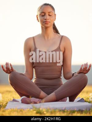 Appréciant son temps dans un jardin de zen. Photo d'une jeune femme sportive méditant tout en faisant de l'exercice à l'extérieur. Banque D'Images