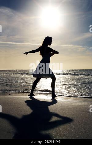 Jeune femme dansant sur la mer. Portrait d'une jeune femme dansant sur la mer - extérieur. Banque D'Images