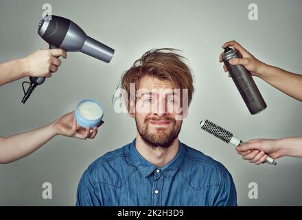 Theres aucune excuse pour ne pas chercher votre meilleur. Studio portrait d'un jeune homme qui se fait un relooking de cheveux sur un fond gris. Banque D'Images