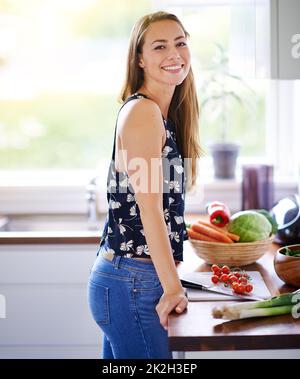 Je me sens aussi bien que je mange. Prise de vue d'une jeune femme préparant un repas dans sa cuisine. Banque D'Images