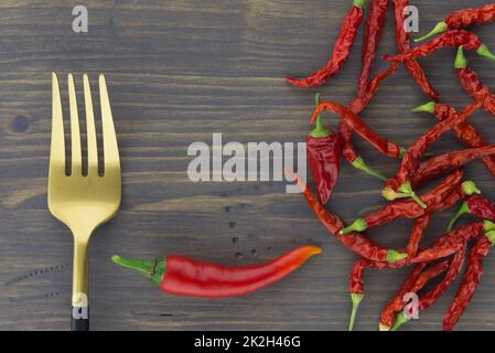 Piments rouges frais et séchés avec des couverts dorés Banque D'Images