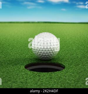 Balle de golf debout près du trou Banque D'Images
