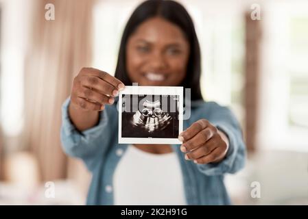 Devinez ce qui rejoint bientôt la famille. Gros plan d'une femme méconnaissable tenant un échogramme à la maison. Banque D'Images