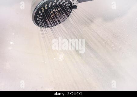 Des gouttes d'eau tombent de l'arrosoir dans la douche de près. Le débit d'eau. Grand arrosoir rond dans la douche Banque D'Images