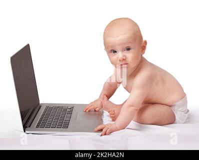 Hes already learning the ways of technology. A baby boy with a laptop. Stock Photo