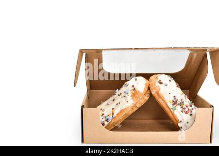 Eclairs dans une boîte en carton sur fond blanc. Boîte en carton de protection jetable avec produits de boulangerie sucrés après la livraison. Banque D'Images
