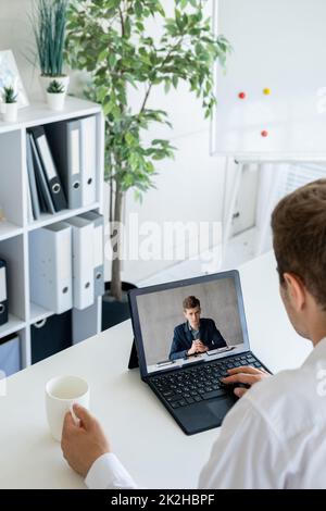 Business teleconference. Video chat. Professional webcast. Male partners discussing project working online using laptop screen in virtual office. Stock Photo