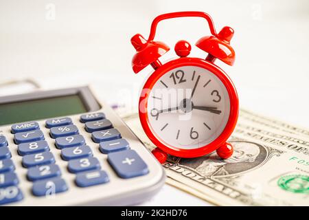 Alarm clock with coins on US dollar banknotes, finance installment loan time. Stock Photo