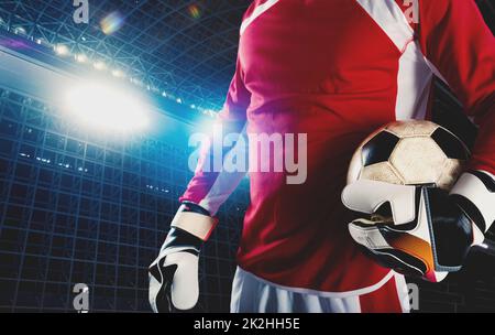 Le gardien de but tient le ballon dans le stade pendant un match de football Banque D'Images