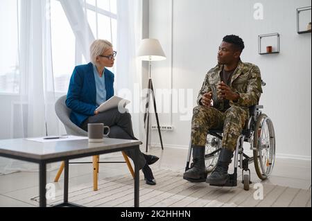 Soldat paraplégique en fauteuil roulant parlant avec un thérapeute Banque D'Images