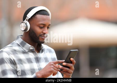 Homme à la peau noire écoutant de la musique marche dans la rue Banque D'Images