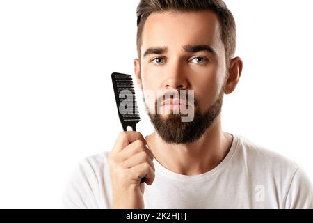 Beau homme bien entretenu peignant sa barbe Banque D'Images