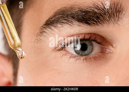 Œil mâle et pipette avec une huile hydratante Banque D'Images