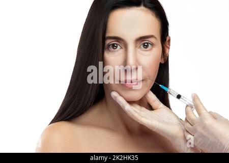 Femme d'âge moyen recevant une injection faciale pour rajeunir la peau Banque D'Images