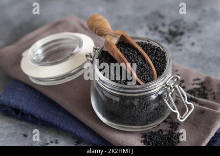 Épices indiennes graines de cumin noir (nigella sativa ou kalonji) dans un pot en verre avec une pelle en bois de gros plan Banque D'Images
