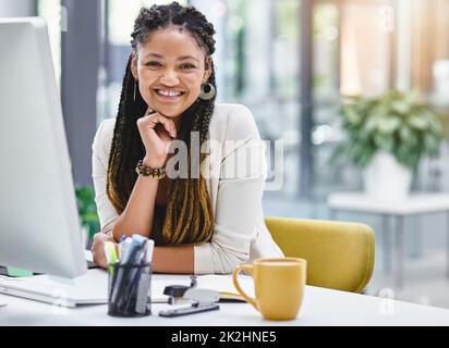 Il n'y a nulle part ailleurs que je préfère travailler. Portrait court d'une jeune femme d'affaires attirante assise à son bureau. Banque D'Images