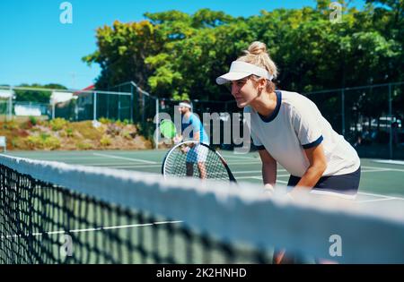 Laissez tout sur le terrain.Photo courte d'une équipe de tennis mixte jouant ensemble sur un court de tennis en plein air. Banque D'Images