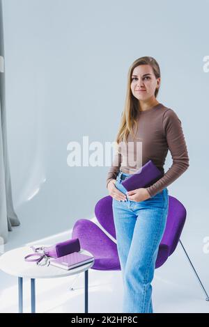 A stylish woman holds a purple leather purse in her hands. Small women's handbag Stock Photo