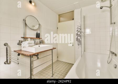 Glass partition between shower tap and wall flush toilet in barhroom at home Stock Photo