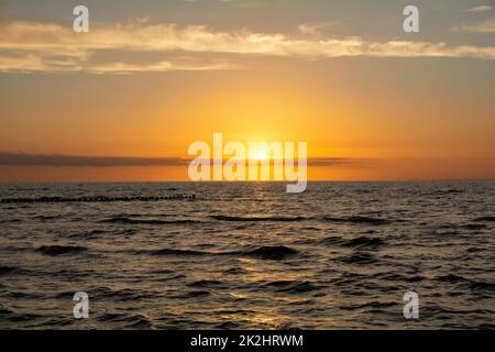 Magnifique coucher de soleil orange sur la mer, avec brise-lames en bois dans l'eau Banque D'Images