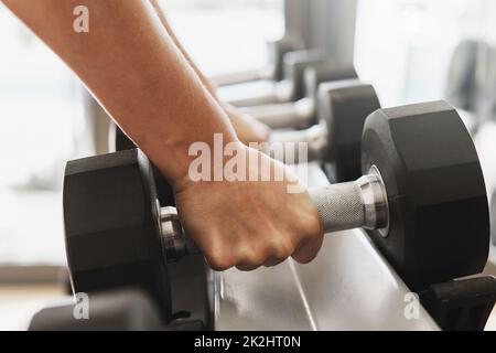 Mains et haltères femelles sur le rack dans la salle de gym Banque D'Images