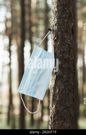 Masque sur l'arbre. Concept de pollution environnementale ou pandémie COVID-19.. Banque D'Images