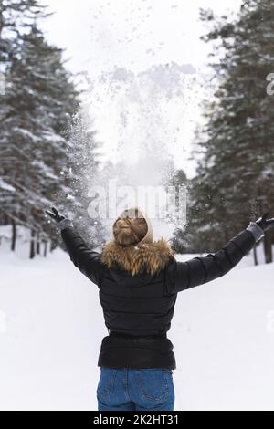 Femme jetant de la neige dans l'air pendant la journée froide d'hiver Banque D'Images