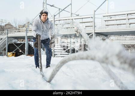 Un jeune athlète s'est sorti avec des cordes de combat pendant la journée hivernale enneigée. Banque D'Images