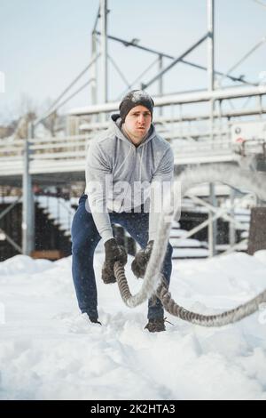 Un jeune athlète s'est sorti avec des cordes de combat pendant la journée hivernale enneigée. Banque D'Images