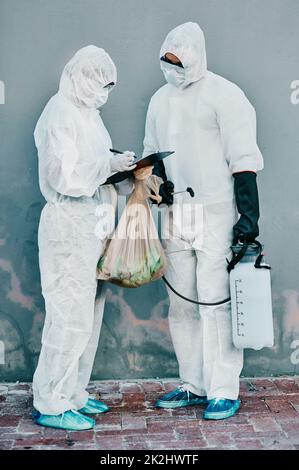 L'unité de lutte contre les virus.Photo de deux travailleurs de la santé portant des combinaisons de matières dangereuses travaillant ensemble pendant une épidémie dans la ville. Banque D'Images