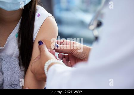 Un bracelet pour votre bravoure.Prise de vue d'une petite fille se faisant vacciner à l'hôpital. Banque D'Images