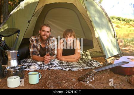 Dans les bois.Photo d'un jeune couple allongé dans une tente en regardant vers l'extérieur. Banque D'Images