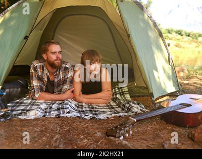 Dans les bois.Photo d'un jeune couple allongé dans une tente en regardant vers l'extérieur. Banque D'Images