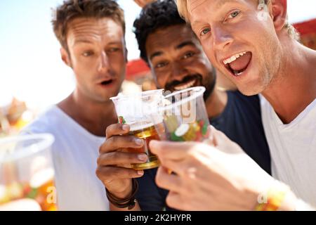 Laissez la fête commencer.Trois jeunes hommes toaster leurs bières lors d'un festival de musique. Banque D'Images