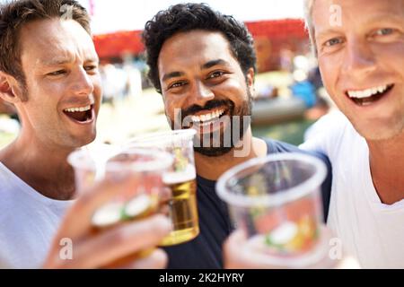 C'est parti !Trois jeunes hommes toaster leurs bières lors d'un festival de musique. Banque D'Images