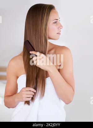 Élimination des enchevêtrements indésirables.Une magnifique femme brunette se brossant ses cheveux longs et sains. Banque D'Images
