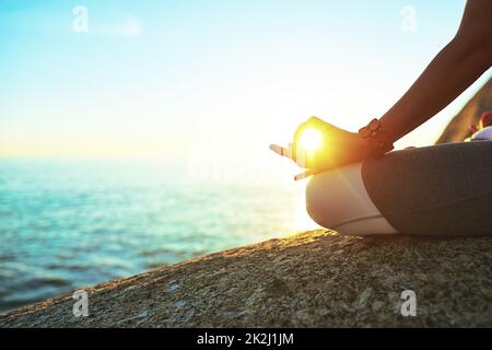 Le cadre idéal pour un calme parfait.Plan court d'une femme pratiquant la pose de lotus sur la plage. Banque D'Images