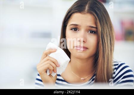 Le printemps signifie allergies pour beaucoup.Portrait d'une jeune femme souffrant d'allergies tenant un tissu à la maison. Banque D'Images